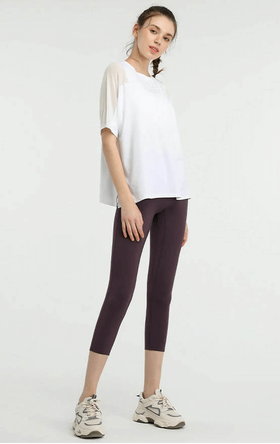 Woman in a loose mesh short sleeve t-shirt and leggings; perfect for running, fitness, cycling, and sports activities.